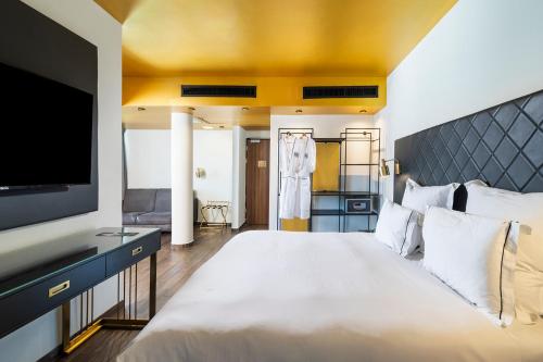 a bedroom with a large white bed and a flat screen tv at EVE Eilat by Adam Hotels in Eilat