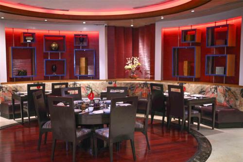 a dining room with tables and chairs and red lighting at Radisson Blu MBD Hotel Noida in Noida