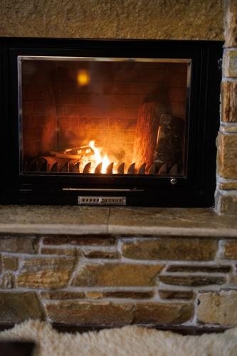 a brick fireplace with a fire in it at Luxury Guesthouse Pantheon in Palaios Panteleimon