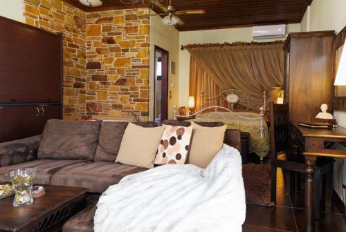 a living room with a couch and a brick wall at Luxury Guesthouse Pantheon in Palaios Panteleimon