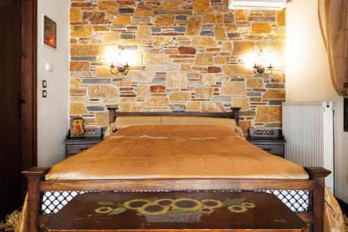 a bed in a room with a stone wall at Luxury Guesthouse Pantheon in Palaios Panteleimon