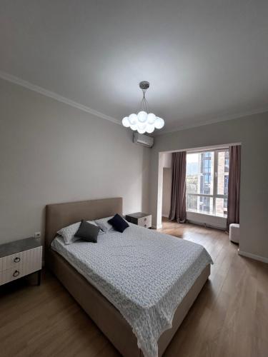 a bedroom with a bed and a large window at Квартира in Almaty