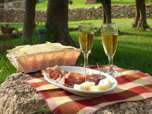 聖特奧多羅的住宿－Agriturismo La Rocca Manna，盘子和两杯葡萄酒