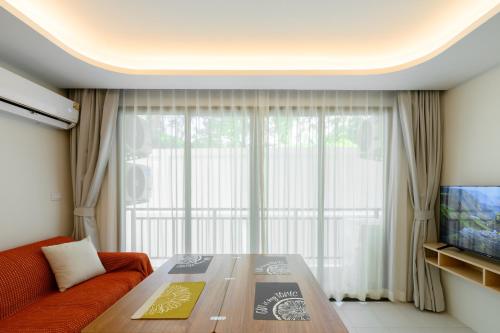 a living room with a table and a large window at Fantasea Condo Kamala A210 2BDRM by Phuket Sabay Rent in Kamala Beach