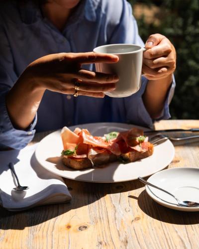 a woman holding a cup of coffee next to a plate of food at Lu. b&b in Cervia