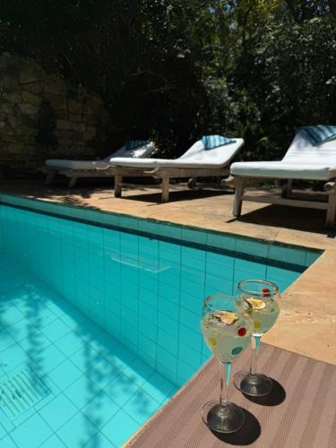 two wine glasses sitting on a table next to a swimming pool at Seaside Villa 1 & Seaside Villa 2 at 'Tamani' in Diani Beach