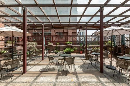 an outdoor patio with tables and chairs and umbrellas at Hotel G7 Taipei in Taipei