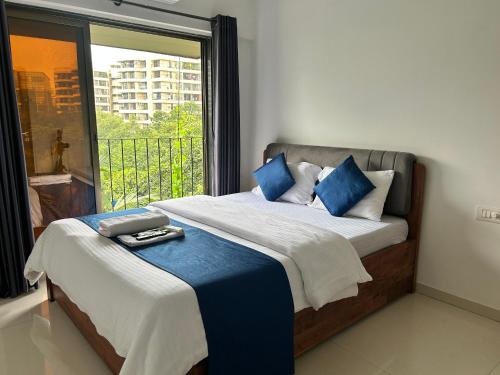 a bedroom with a bed with blue pillows and a window at Zenith Service Apartments - Entire 2BHK Near Mumbai Airport and IIT Powai in Mumbai