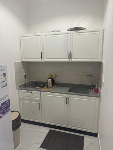 a kitchen with white cabinets and a sink at شقق المها وصول ذاتي in Hafr Al Baten