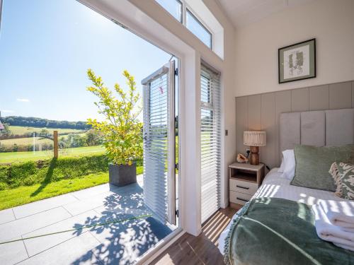 Un dormitorio con una cama y una ventana grande. en Stylish 3-bed Lodge With Golf & Spa Access, en Hemborough Post