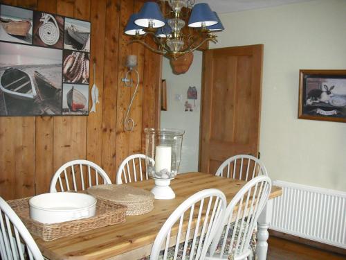 a dining room table with white chairs and a candle on it at Charmantes Cottage im Landhausstil in Kearsney, Dover 