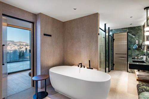 a bathroom with a white tub and a large window at Swissôtel Tbilisi in Tbilisi City