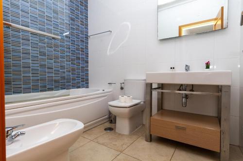 a white bathroom with a sink and a toilet at Palmeiras Paz Apartment in Lagos