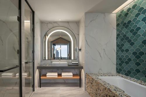 a bathroom with a tub and a sink and a mirror at Sheraton Johor Bahru in Johor Bahru
