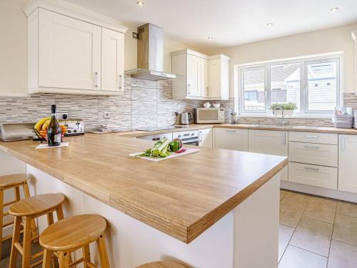 a kitchen with white cabinets and a wooden counter top at Gwbert Holiday Cottages, Riversmouth in Gwbert
