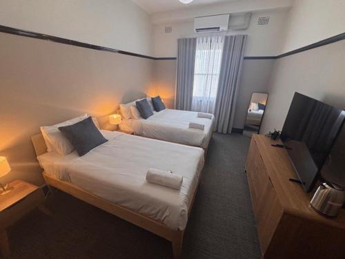 a hotel room with two beds and a television at Strathfield Hotel in Sydney