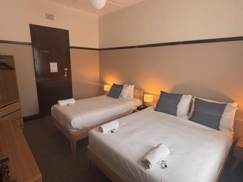 a hotel room with two beds and two lamps at Strathfield Hotel in Sydney