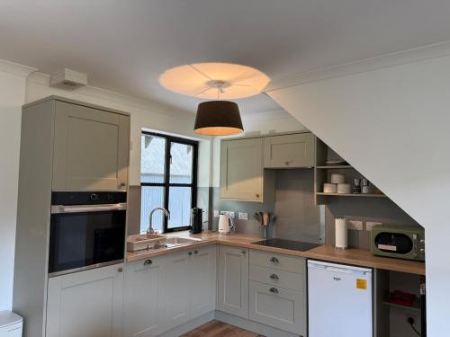 a kitchen with white cabinets and a light fixture at Highland Nook for 4 in Fort William