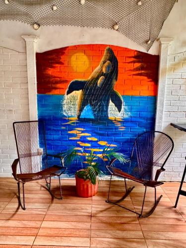 a mural of a breaching whale on a wall at Villas Ela en Bahía Ballena,Uvita Hermosas habitaciones privadas grandes, piscina, cocina, jacuzzi, aire acondicionado, tv y baño privado in Uvita