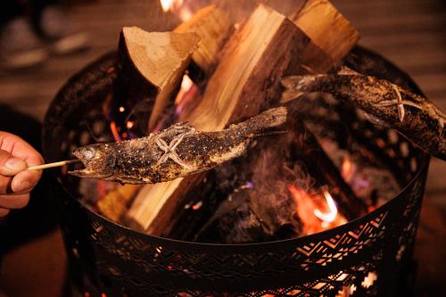 a person holding a piece of food over a fire at From P in Hakuba