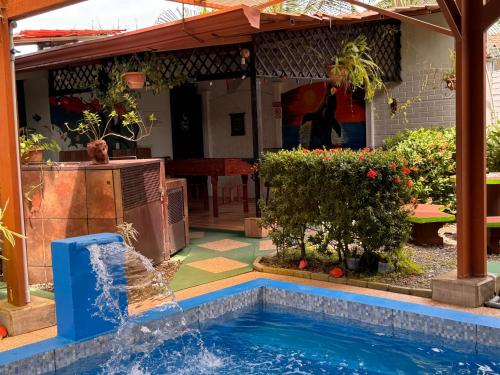 a swimming pool with a fountain in a yard at Villas Ela en Bahía Ballena,Uvita Hermosas habitaciones privadas grandes, piscina, cocina, jacuzzi, aire acondicionado, tv y baño privado in Uvita