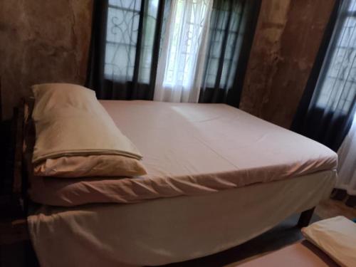 a small bed in a room with windows at Belmoro Transient House in Bacacay