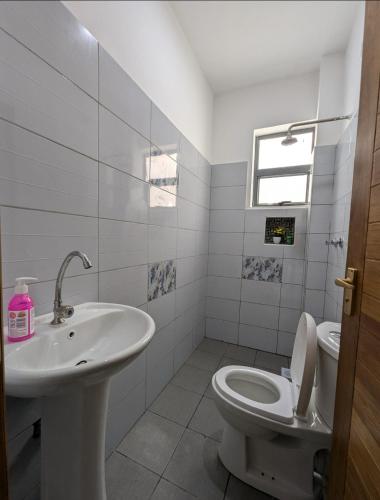 une salle de bain blanche avec un lavabo et des toilettes dans l'établissement Nancy's Haven studio apartment, à Mombasa