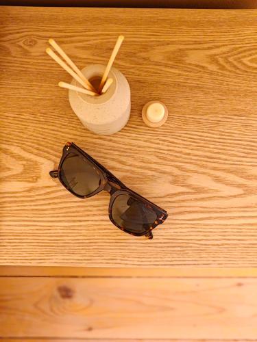 a pair ofsunglasses and a drink on a wooden table at DESERT Ezuz in ‘Ezuz