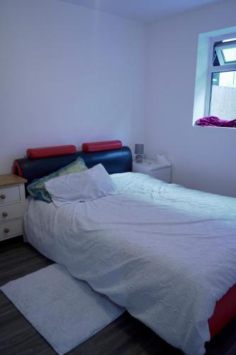 a bedroom with a bed with white sheets and a window at Avonmouth studio apartment in Bristol