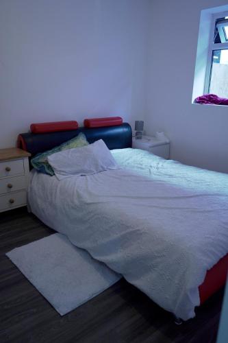 a bedroom with a bed with white sheets and a window at Avonmouth studio apartment in Bristol