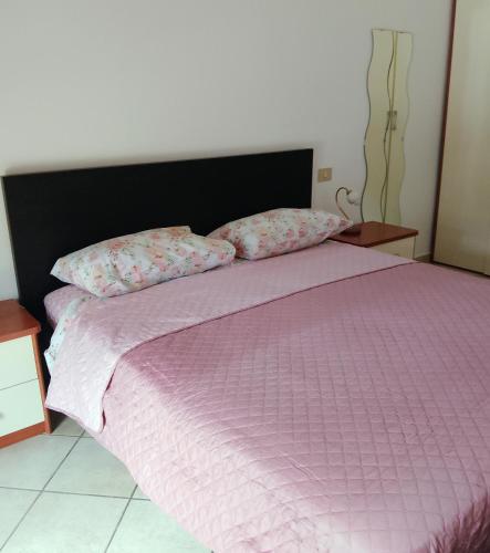 un letto con piumone rosa e 2 cuscini di Casa loto a Pantigliate