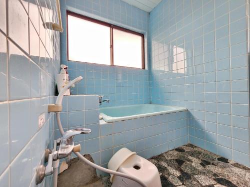 a blue bathroom with a toilet and a bath tub at まんのう清流庵 in Manno