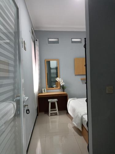a small bedroom with a bed and a mirror at Ambu Guest House in Bandung