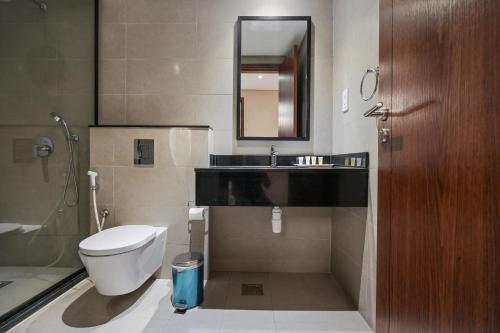 a bathroom with a toilet and a sink and a mirror at Eden Garden Hotel Apartment in Manama