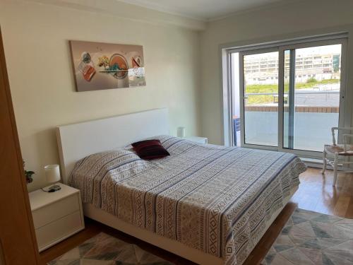 a bedroom with a bed and a large window at Apartamento de Férias in São Félix da Marinha