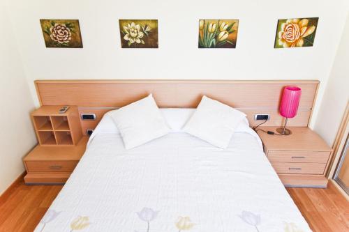 a bedroom with a white bed with a pink lamp at TECAVI II Atic Planetcostadorada in La Pineda
