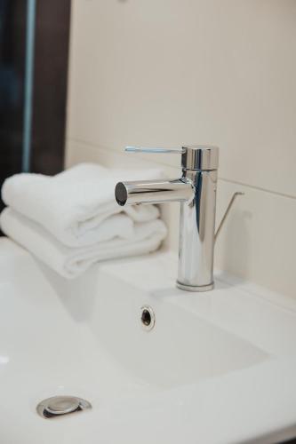 a bathroom sink with a faucet and white towels at Parkhotel IV Jahreszeiten Kühlungsborn in Kühlungsborn