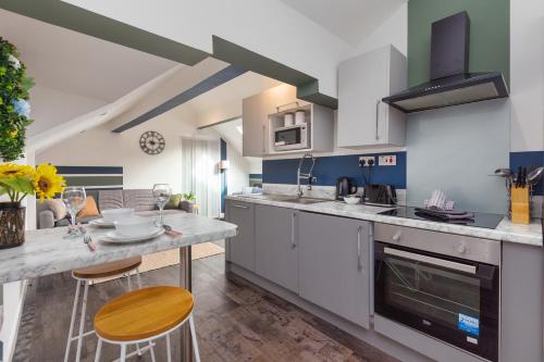 a kitchen with white cabinets and a table with chairs at Charles Alexander Short Stay - South Pier Apartments in Blackpool