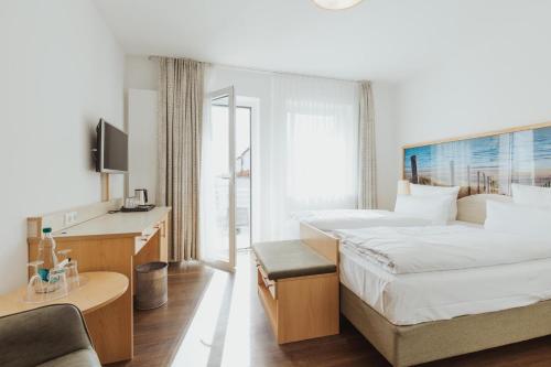 a hotel room with two beds and a television at Parkhotel IV Jahreszeiten Kühlungsborn in Kühlungsborn