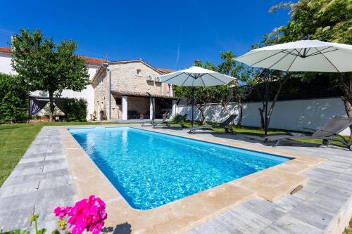 une piscine avec deux parasols à côté d'une maison dans l'établissement Stone House Furlani, à Svetvinčenat