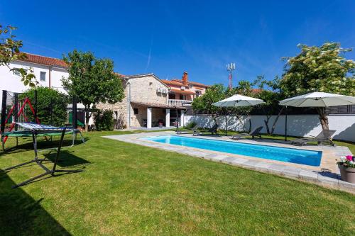 - une piscine dans une cour avec des parasols dans l'établissement Stone House Furlani, à Svetvinčenat