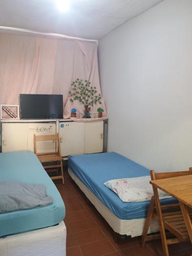 Cette chambre comprend deux lits, un bureau et une table. dans l'établissement Refúgio 3rd, à Piraí
