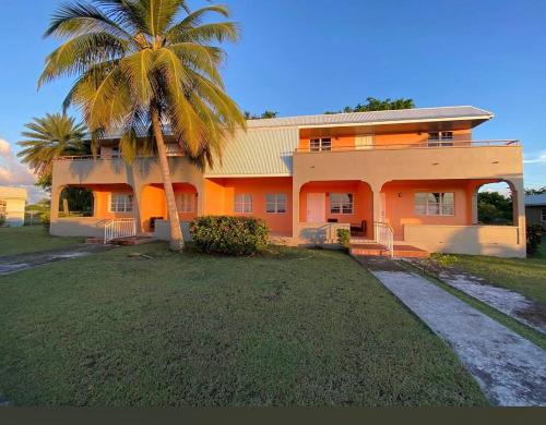 a house with a palm tree in front of it at Dove Cove Comfort Suites in Rat Island
