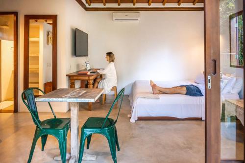 a woman is sitting at a table in a room at Pousada Vila Biribiri Trancoso in Trancoso