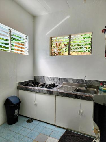 a kitchen with a sink and a stove and two windows at Casa de Lucas in Moalboal