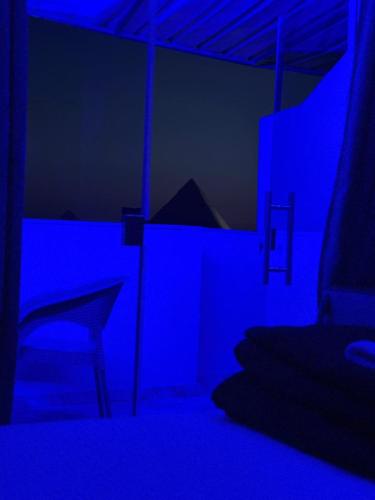 a blue room with a bed and a chair at Rost pyramids view in Cairo