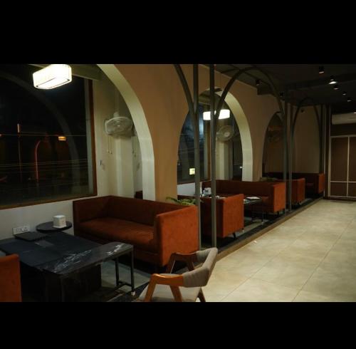 a living room with a couch and a table and chairs at Mosaic Hotel & Bar in Hanumāngarh