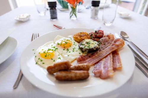 a plate of eggs and bacon and toast on a table at Cosimi Guest House in Durbanville