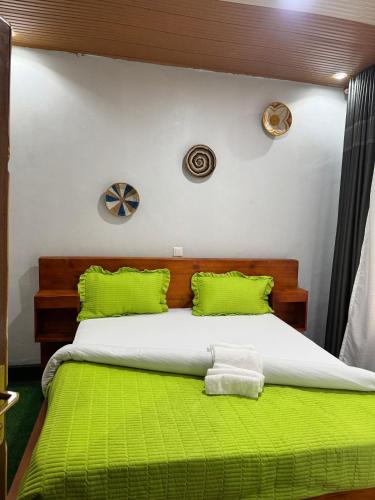 a bedroom with a bed with green sheets and pillows at Vilimani Garden Residence in Rwamagana