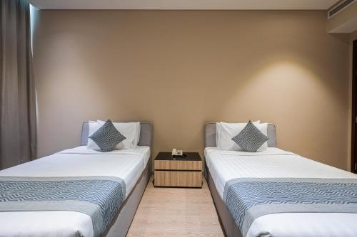 two beds sitting next to each other in a room at Eden Garden Hotel Apartment in Manama